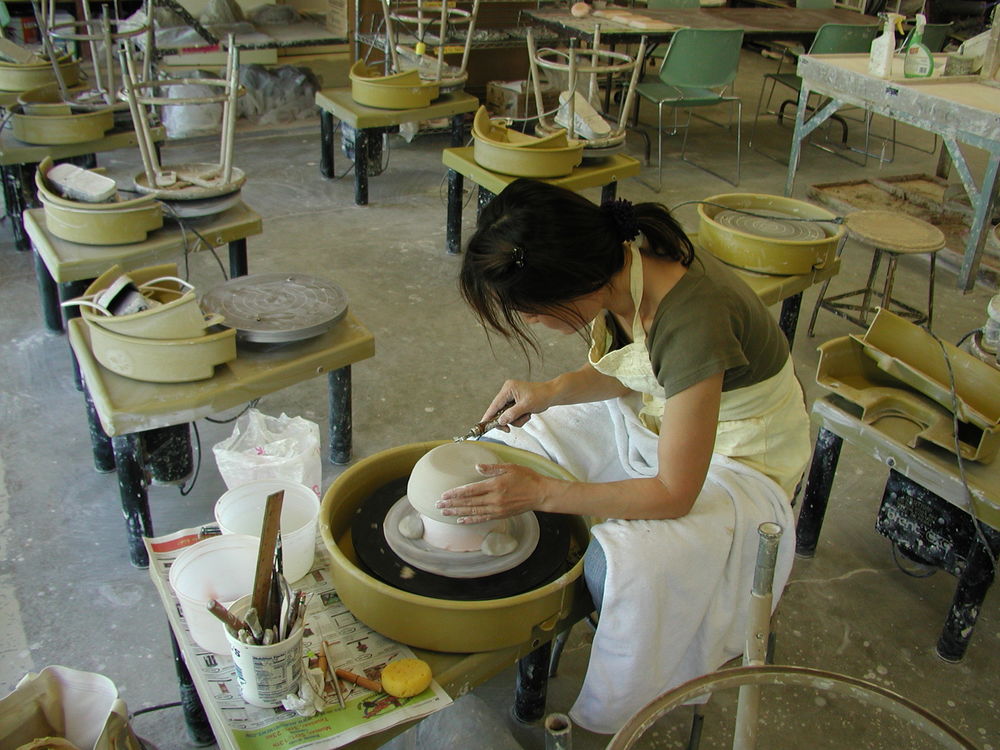 Woman with long dark hair working at a pottery wheel